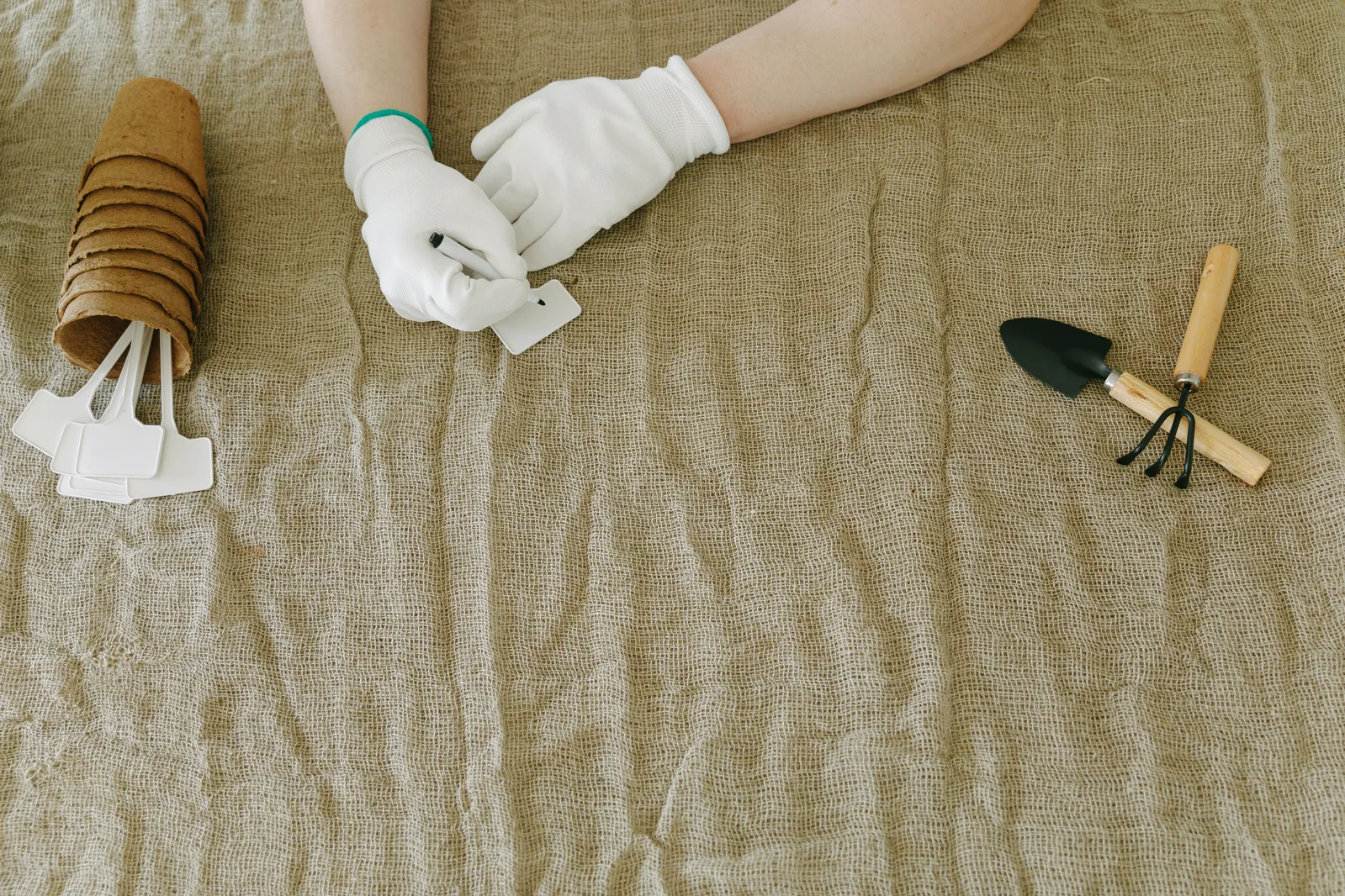 A person in white gloves writing plant tags