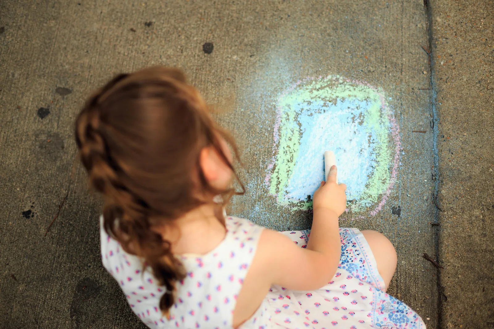 Little girl drawing on pavement
